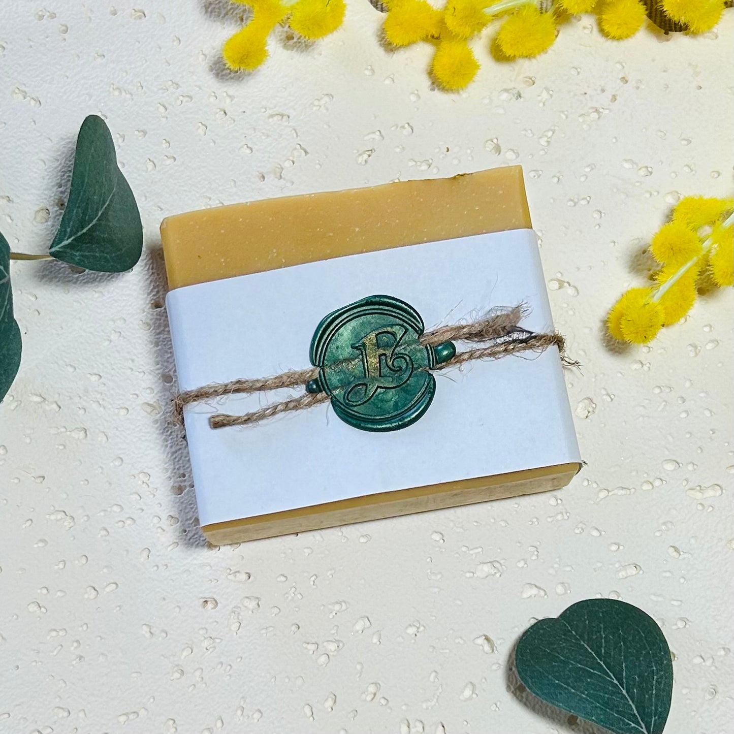 Yellow soap, white paper band with string wrapped around and green wax seal